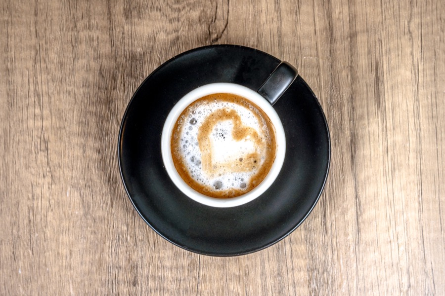 Latte with heart foam art in a black cup