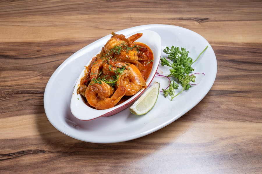 Shrimp in red sauce with herbs on a white dish