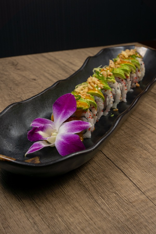 Sushi roll with avocado and a purple orchid