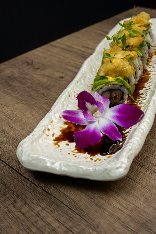 Sushi roll with eel sauce and an orchid