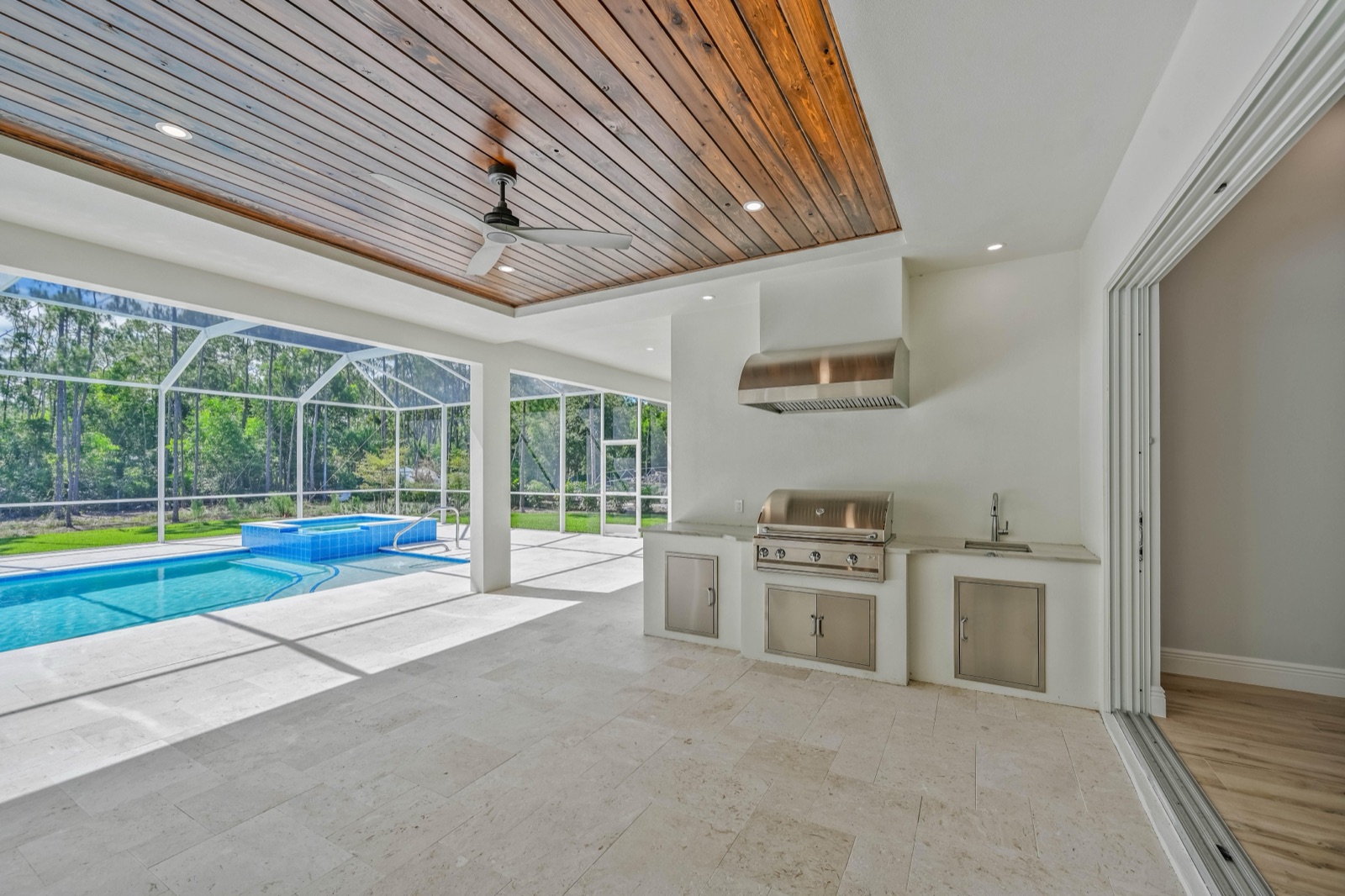 Outdoor kitchen next to a screened pool